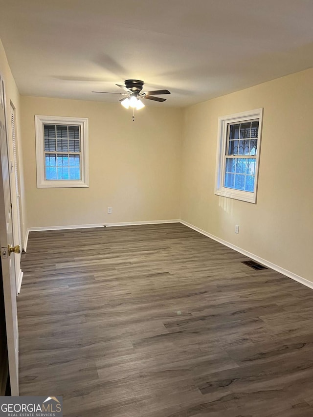 empty room with ceiling fan and dark hardwood / wood-style flooring