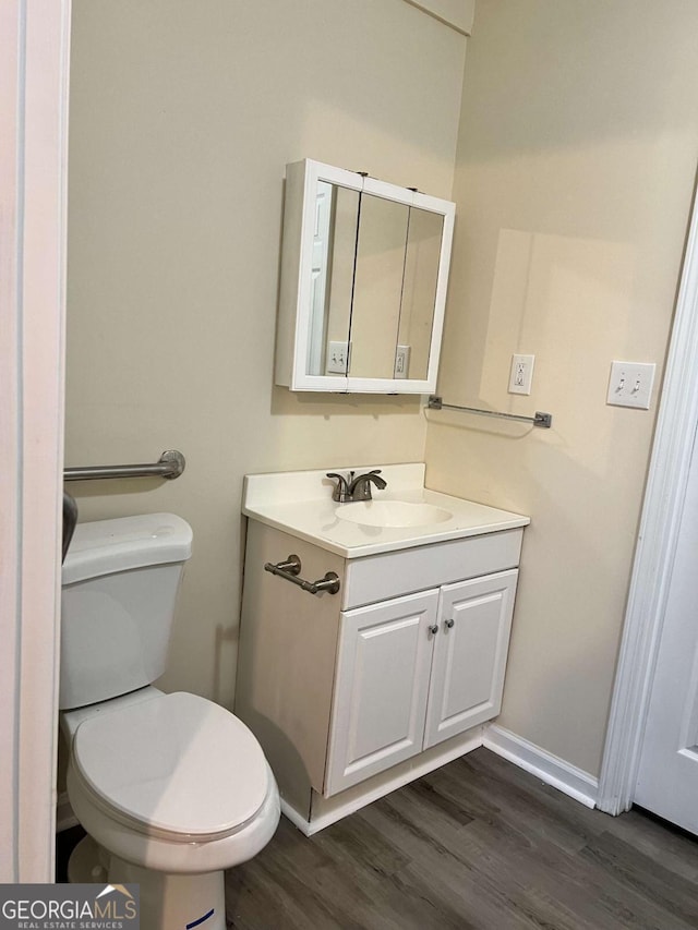 bathroom with toilet, vanity, and hardwood / wood-style flooring