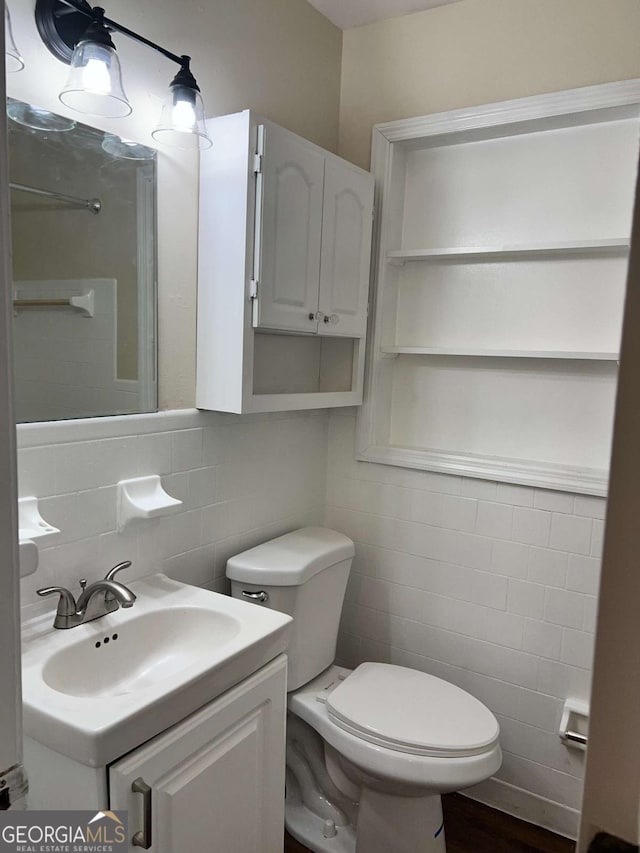 bathroom with toilet, tile walls, tasteful backsplash, and vanity