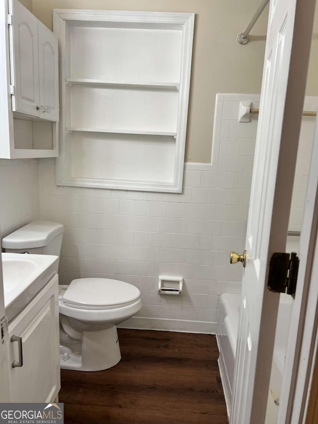 bathroom with tile walls, toilet, wood-type flooring, and vanity