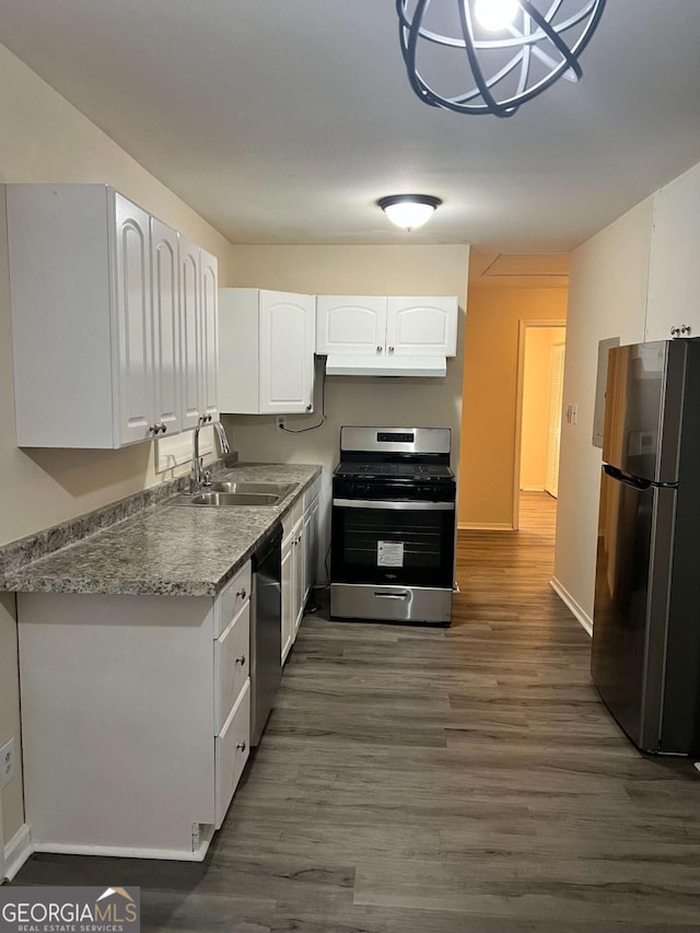 kitchen with stainless steel appliances, sink, white cabinets, light stone countertops, and dark wood-type flooring