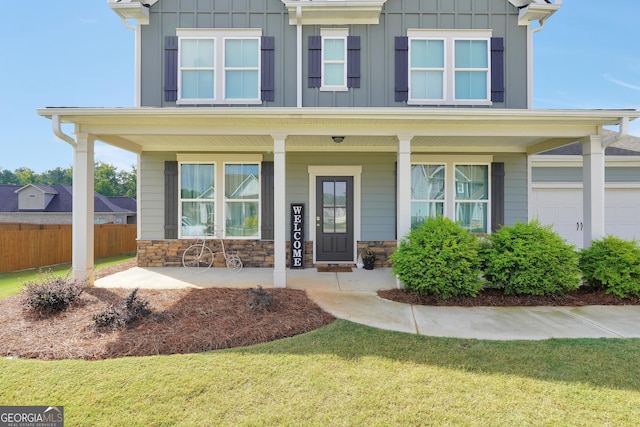 view of front of house featuring covered porch, a garage, and a front yard