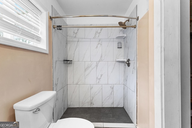 bathroom featuring a tile shower and toilet