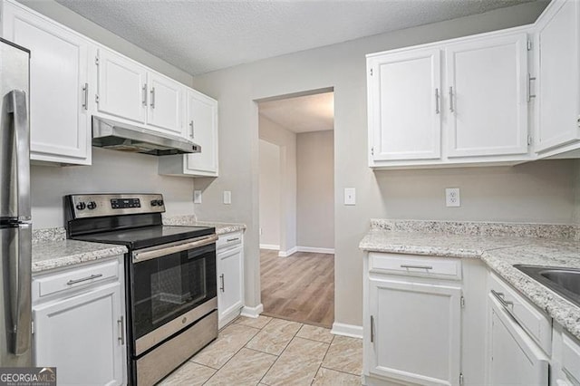 kitchen with a textured ceiling, stainless steel appliances, white cabinetry, and light tile patterned floors