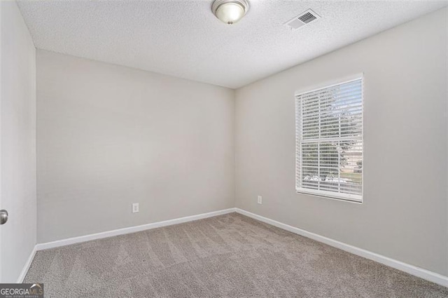 spare room with a textured ceiling and carpet