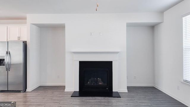 interior space featuring white cabinets, stainless steel fridge, and hardwood / wood-style flooring