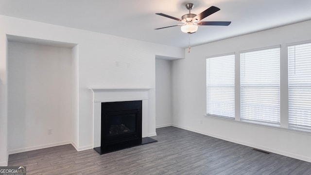 unfurnished living room featuring dark wood-type flooring, ceiling fan, and plenty of natural light