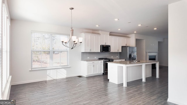 kitchen with a center island with sink, white cabinetry, pendant lighting, and appliances with stainless steel finishes