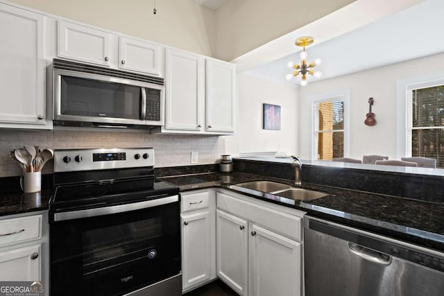 kitchen featuring stainless steel appliances, dark stone counters, white cabinets, and sink