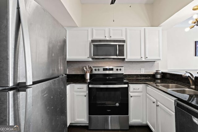 kitchen with sink, white cabinets, dark stone counters, dark tile patterned floors, and appliances with stainless steel finishes