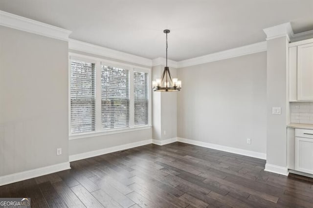 unfurnished dining area with dark wood-type flooring, ornamental molding, and an inviting chandelier