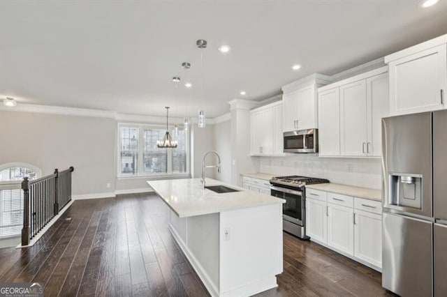 kitchen with white cabinetry, stainless steel appliances, sink, and an island with sink