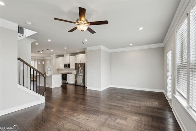 unfurnished living room featuring sink, dark wood-type flooring, ornamental molding, and ceiling fan