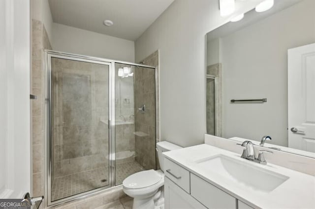 bathroom featuring vanity, a shower with shower door, and toilet