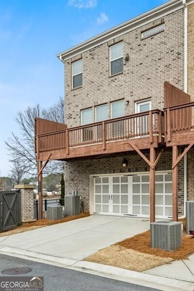 rear view of house featuring a wooden deck, a garage, and central air condition unit