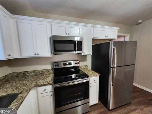 kitchen featuring white cabinets, appliances with stainless steel finishes, dark stone countertops, and dark hardwood / wood-style flooring