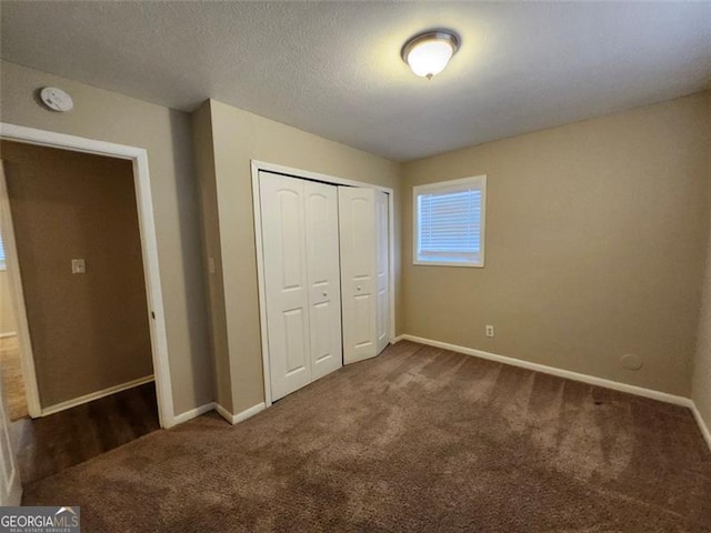 unfurnished bedroom with dark colored carpet and a closet