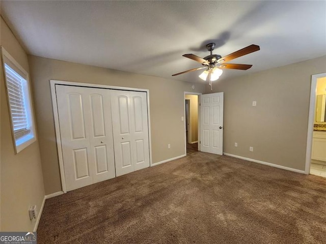 unfurnished bedroom featuring a closet, ensuite bathroom, ceiling fan, and dark carpet