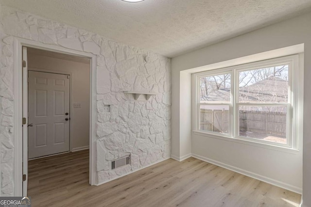 unfurnished room featuring a textured ceiling and light hardwood / wood-style floors