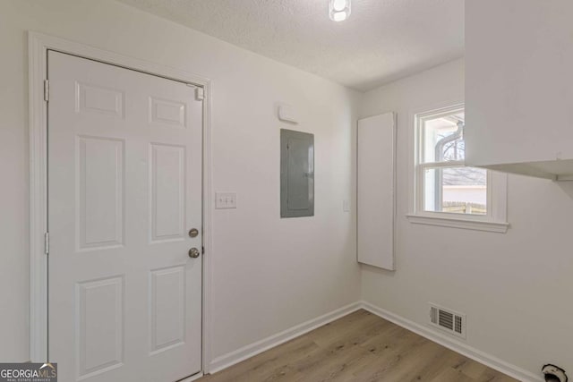 interior space featuring light hardwood / wood-style floors, a textured ceiling, and electric panel