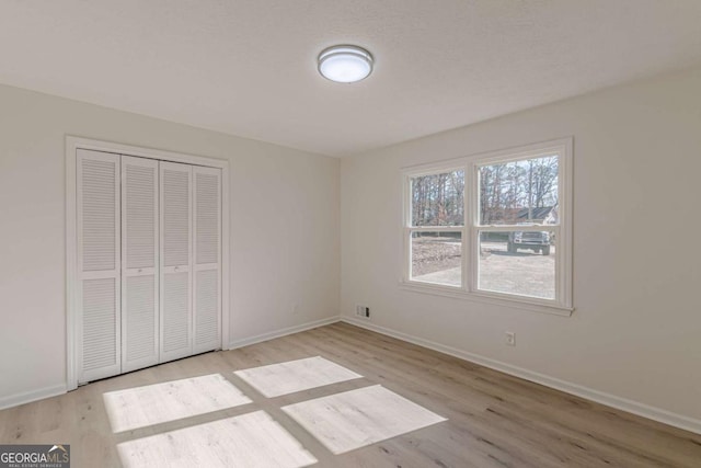 unfurnished bedroom with light hardwood / wood-style flooring and a closet