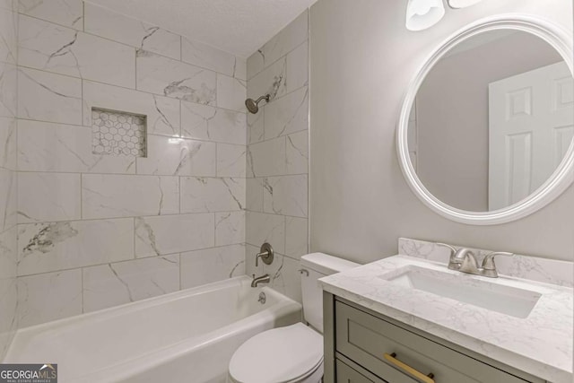 full bathroom featuring a textured ceiling, toilet, vanity, and tiled shower / bath