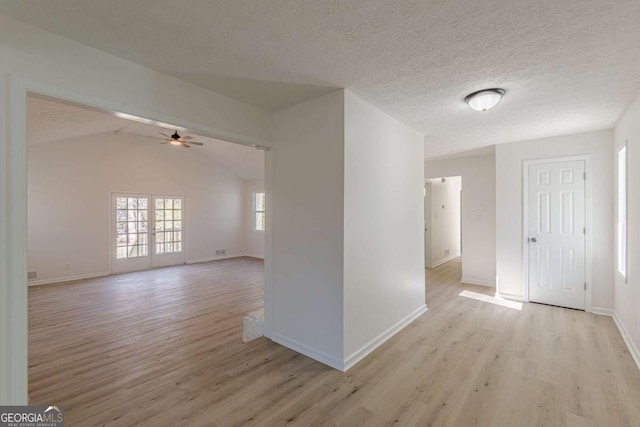 spare room with light hardwood / wood-style floors, ceiling fan, lofted ceiling with beams, and a textured ceiling