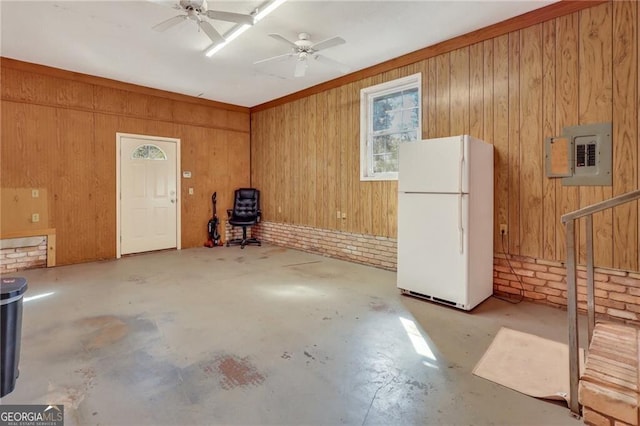 garage featuring electric panel, ceiling fan, white fridge, and wooden walls