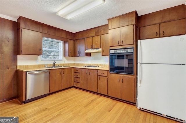 kitchen featuring white fridge, a textured ceiling, sink, oven, and stainless steel dishwasher