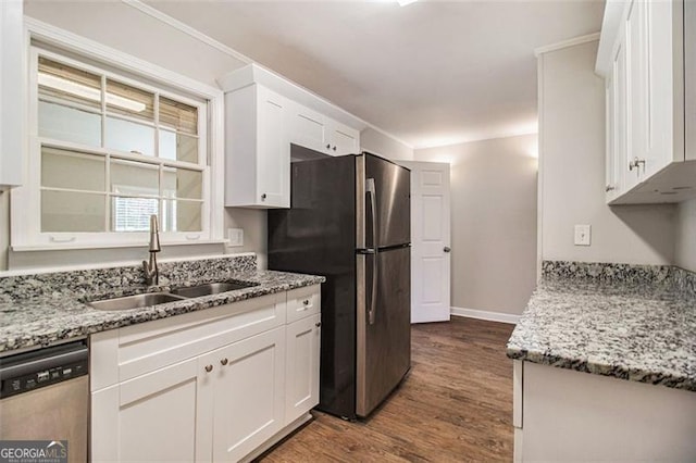 kitchen with stainless steel appliances, white cabinets, sink, and light stone countertops