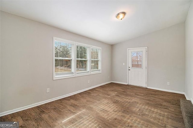 spare room featuring dark hardwood / wood-style flooring and vaulted ceiling