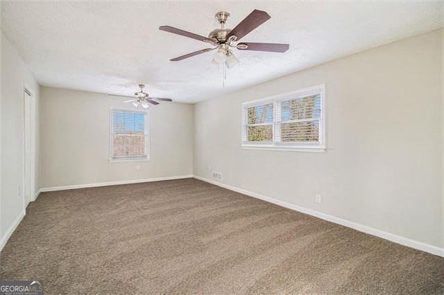 empty room featuring a textured ceiling, carpet floors, ceiling fan, and a healthy amount of sunlight