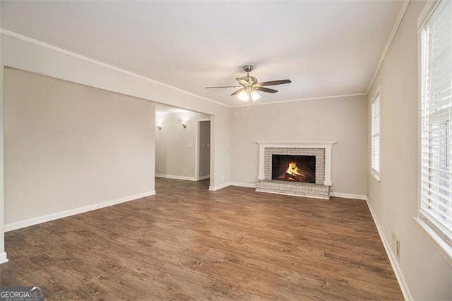 unfurnished living room featuring a brick fireplace, dark wood-type flooring, ceiling fan, and ornamental molding