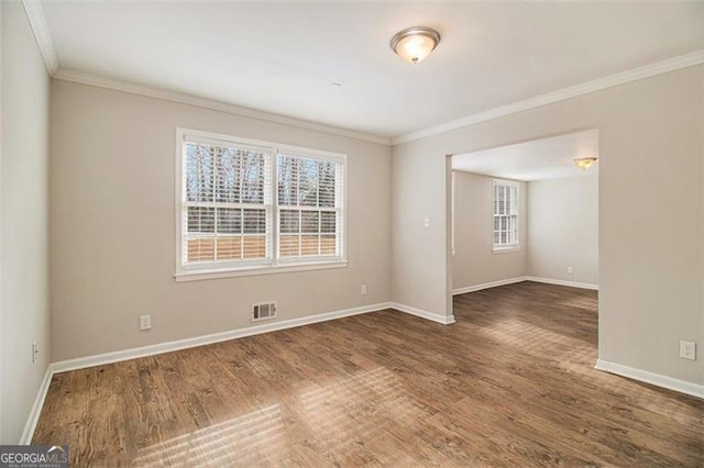 spare room featuring ornamental molding, dark hardwood / wood-style flooring, and plenty of natural light