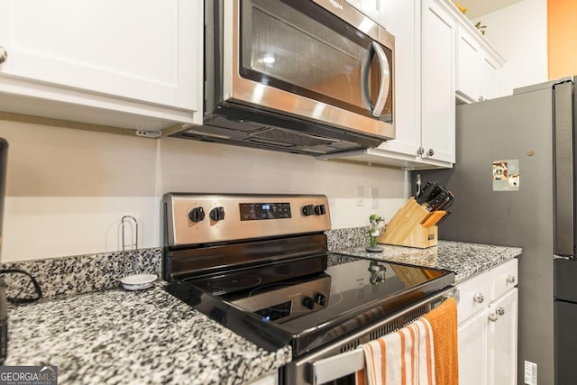 kitchen featuring stainless steel appliances, white cabinets, and light stone countertops