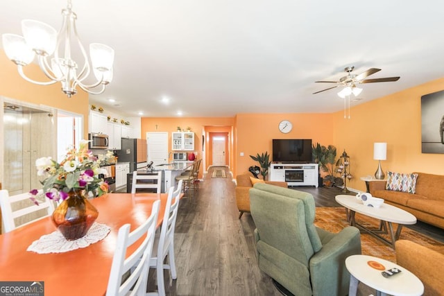 dining area featuring ceiling fan with notable chandelier and dark hardwood / wood-style floors