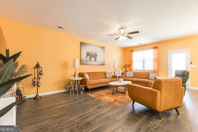 living room featuring ceiling fan and dark wood-type flooring