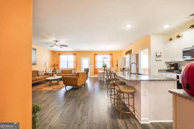 kitchen with a kitchen breakfast bar, a center island with sink, dark hardwood / wood-style floors, sink, and white cabinetry