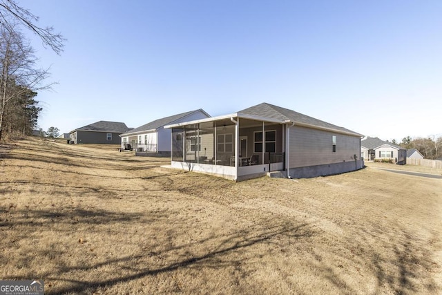 rear view of house with a yard and a sunroom