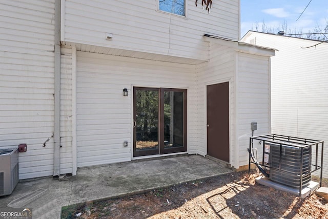 view of exterior entry with central AC unit and a patio area