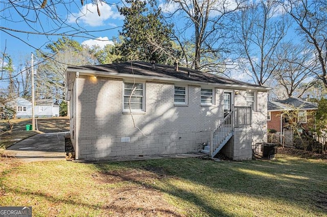 rear view of house featuring central air condition unit and a lawn