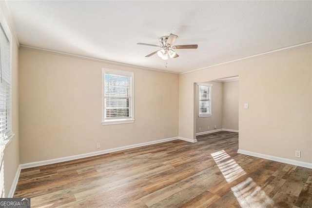 empty room with a healthy amount of sunlight, crown molding, and hardwood / wood-style flooring