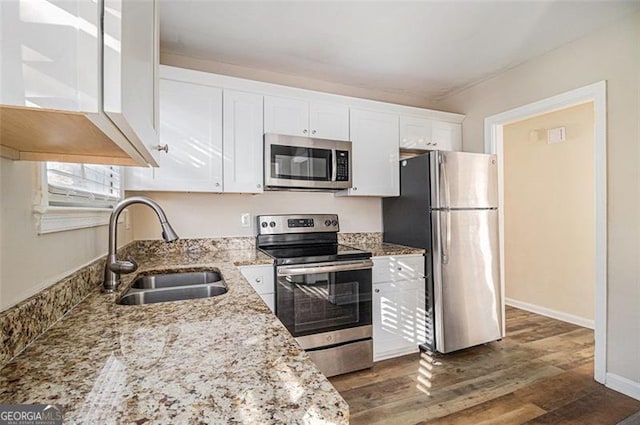 kitchen featuring appliances with stainless steel finishes, dark hardwood / wood-style flooring, light stone counters, white cabinets, and sink