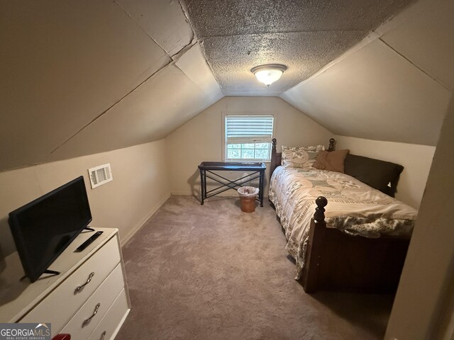 bedroom with a textured ceiling, vaulted ceiling, and light carpet