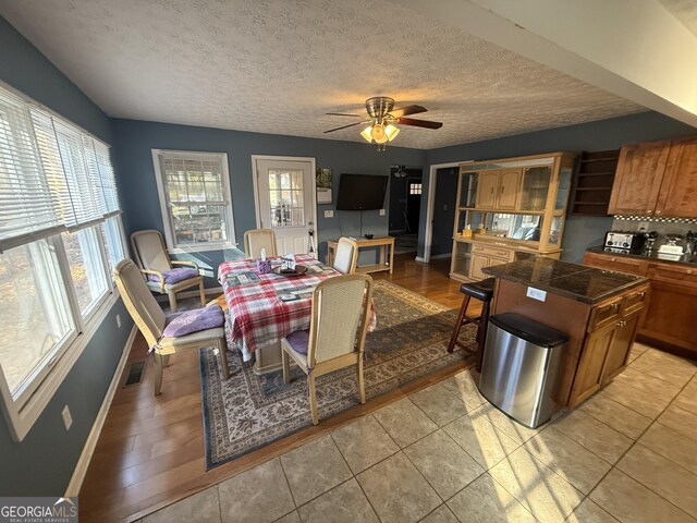 tiled dining room featuring a textured ceiling and ceiling fan