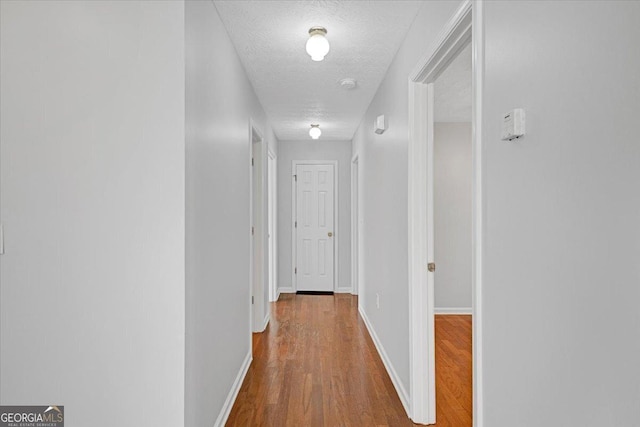 hallway with a textured ceiling and hardwood / wood-style floors