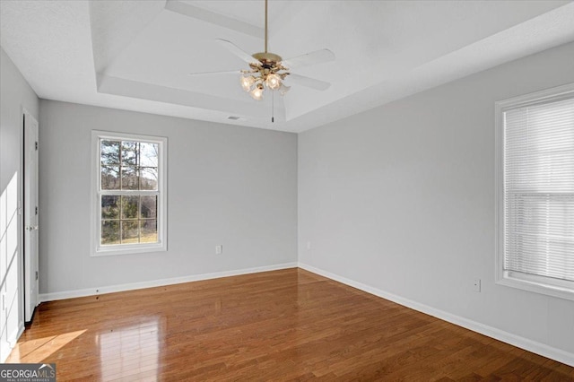 spare room with ceiling fan, hardwood / wood-style floors, and a raised ceiling