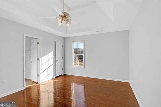 unfurnished room featuring hardwood / wood-style flooring, a textured ceiling, a raised ceiling, and ceiling fan