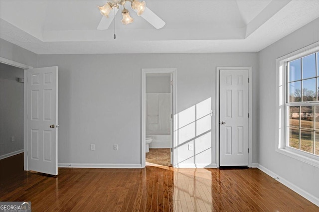 interior space featuring ceiling fan, dark wood-type flooring, and a tray ceiling