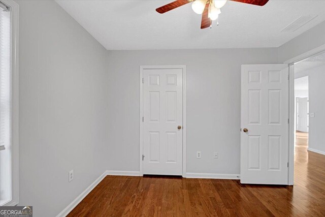 unfurnished bedroom with ceiling fan and dark hardwood / wood-style flooring